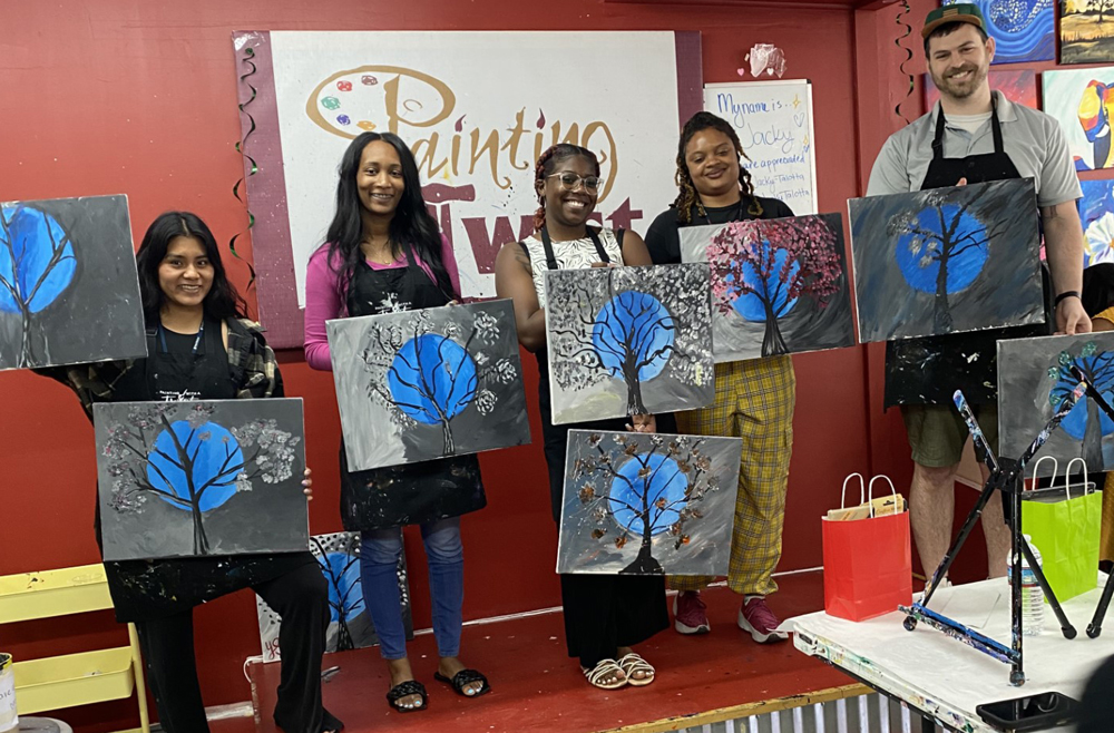 Blended Case Management Case Managers Beatrice Carrillo, Brittany McNeil, Bianca Ogelsby, Fatima Joshua, and ACCESS Case Manager Leo Porth holding paintings of trees